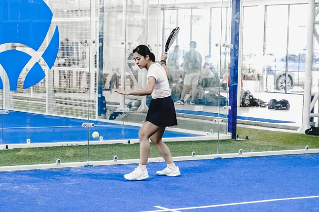 A padel player lining up a forehand on a blue court